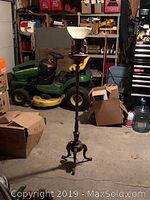 Full view of vintage torchiere floor lamp standing upright in a garage with lawn mower and boxes in background.