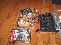 PlayStation 2 slim console accessories and stack of game cases with visible cables.