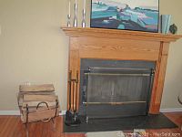 Full view of fireplace mantel with fire screen, fireplace tools, and wood holder with firewood stacked beside it