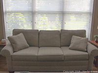 Front view of entire sofa with two throw pillows against windowed wall