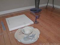 View of Cala Lily platter, signed stoneware serving dish with dip bowl, and blue blown glass candy dish on wooden floor.