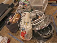 Photo showing a variety of foil serving trays stacked, Wilton baking pans, rolls of liners, and some kitchen items in bags.