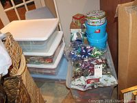Photo of stacked plastic totes with lids filled with colorful gift bows and gift boxes arranged on top and beside the totes.