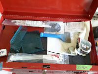 Red Craftsman tool chest drawer partially open showing disorganized small tools, plastic zip ties, measuring tape and manuals.