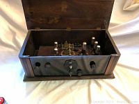 Open wooden box showing inside view of antique tube radio with vacuum tubes and electronic components.