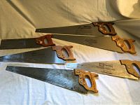 Six professional hand saws laid out showing wooden handles and full blades