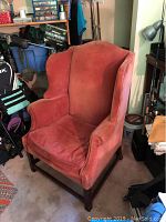 View of the antique wing chair showing front and side angles, highlighting velvet fabric and chair condition.