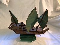 Front and side view of wooden model ship with green sails showing overall condition and details of rigging and hull.