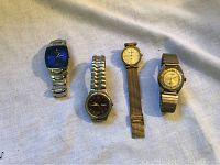 Four watches laid out on fabric: Fossil with blue dial, Kronoron with brown dial, Sergio Valente gold-tone mesh, and Pristine with silver/gold tones.