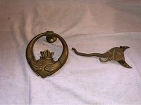 Both antique brass door knocker and vintage elephant hanger laid flat on cloth background.