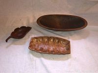 Three wooden serving bowls on light fabric: one large oval, one rectangular segmented, one small leaf-shaped