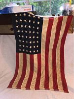 Full view of the 48 star American flag showing the entire flag hanging vertically, stars on the upper left.