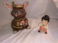 Photo showing vintage rabbit cookie jar seated with large ears, blue eyes, and yellow paint details next to a small Big Boy figurine in red and white checkered overalls.