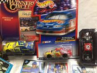Lot showing three diecast race cars in packaging along with assorted collectible cards below