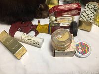 Close up of multiple vintage perfume bottles and containers including one shaped like an Egyptian figure alongside box packaging