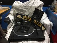 Overall view of Kenwood turntable with PD103 speaker simulator and Cutty Sark bar piece on white cloth.