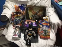 Photo showing lot of collectible toys including WWE, Iron Man 2 figure, Smallville Batman plush, Dinosaur Rex figure, Disney Princess figurine.