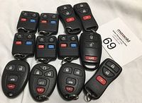 Overview of all thirteen assorted car key remotes with different button layouts and shapes