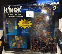 Box front showing the assembled K'NEX Hornet Swarm Dueling Coaster with motor and 4 cars, featuring the colorful construction pieces and roller coaster design.