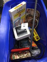 Photo of blue bin showing an assortment including boxed wall installation kit, Sony Hawaiian radio, animal wall installation kit, magazines, power strips, and a small box.