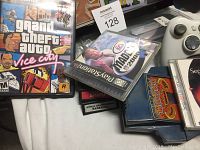 Close-up of Grand Theft Auto Vice City PlayStation 2 game disc case alongside Madden NFL 2003 disc and Xbox 360 wireless controller.