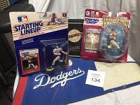 Photo showing two vintage Starting Lineup baseball player figurines in original sealed packaging, one representing Dodgers and another from Cooperstown Collection, placed on cloth banners from Padres and Dodgers.