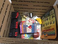Overview of miscellaneous items in box including bobblehead, model kit, craft supplies, and collectibles
