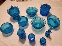 Front view of entire dark blue depression glass collection laid out on table showing all different piece types and shapes.