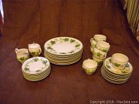 Full lot of vintage Franciscan Ivy china set with all components spread out: dinner plates, dessert plates, cups, saucers, creamer, and sugar set