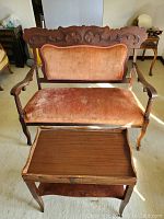 Antique settee with wood carved frame and upholstered seat and back, seated behind a solid wood double tiered end table.