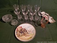Photo showing all stemware glasses, candy dishes, decorative plate, and glass baskets on green cloth background