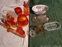 Collection of red to yellow and amber glassware items along with clear glass relish dishes and a pink floral fine china bowl.