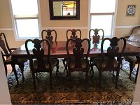 Full view of dining table and six chairs from one side showing table surface and chair backs