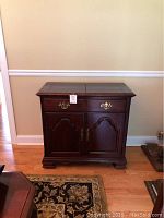 Full frontal view of closed cherry wood serving cart with dual doors and drawer, showing condition and hardware details.