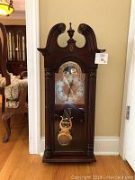 front view of cherry wood case and glass door showing brass dial and pendulum
