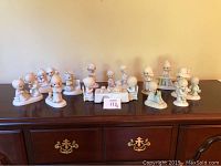 Lot of 12 Precious Moments figurines displayed on wooden surface including group Thanksgiving table set, children figurines in various poses.
