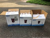 Three boxes of Solo paper hot cups placed on an outdoor surface showing quantity and packaging