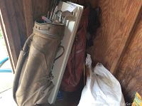 Golf bags set in a shed with visible wear and soiling, several golf clubs inside the front bag.