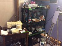 Black plastic shelving unit with multiple shelves and storage items placed on and around it in a laundry room.