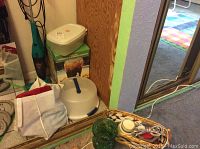 Full view of the lot items including the Bissell vacuum, beverage dispenser, and cake carrier positioned near a mirror in a laundry room