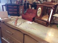 Top view of a dresser showing three wooden jewelry boxes and various costume necklaces arranged on the surface