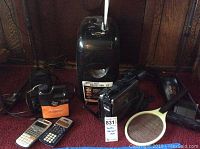 Full lot view showing all items including shredder, fog machine with fog juice, Hitachi VHS video recorder, vacuum, calculators, and bug zapper tennis racket