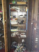 Wooden cabinet showing multiple shelves with various toys, batteries, paper, and small items stored inside.