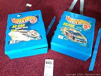 Two blue Hot Wheels 48-car carry cases with Mattel logo on lid, both closed and placed side by side on carpet.