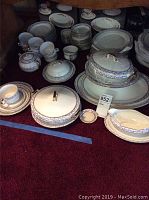 Photo showing the full set laid out including plates, bowls, cups, and serving dishes.