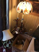 Photo showing the lighthouse glass shade lamp, additional lamp shades, and American Indian figurines on the laminate top table.