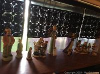 Wide shot of the assortment of figurines gathered on wooden surface, showing various styles and sizes under black patterned curtains.