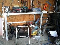 Full view of aluminum workbench with York vise mounted on left corner, various tools stored around and underneath bench.