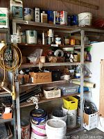 Wide view of workshop metal shelving filled with various chemicals, electrical components, wires, fuses, and workshop supplies.