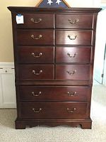 Front view of cherry wood dresser showing ten drawers and brass handles
